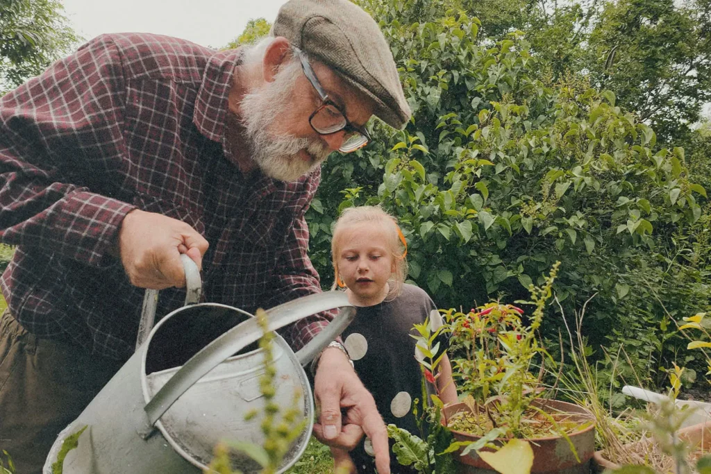 older man teaching a young girl in a garden