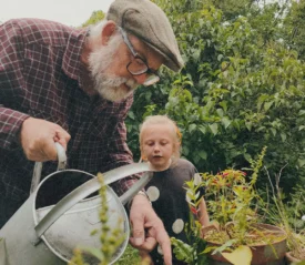 older man teaching a young girl in a garden