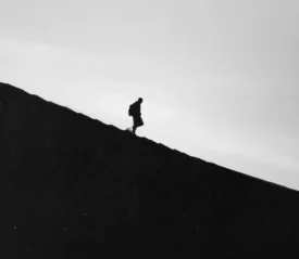 Black and white image of man walking down a steep slope