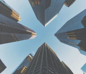 Upward view of tall skyscrapers forming a cross‑shaped opening toward the sky