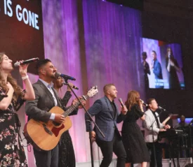 worship team in suits and dresses singing and playing instruments