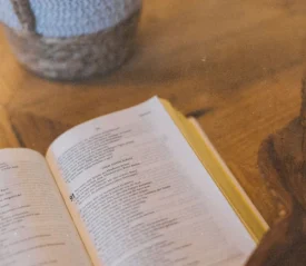 Open Bible laying on a wooden table with warm light and a woven basket in the background