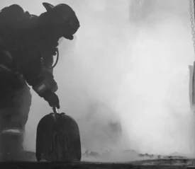 fully suited firefighter in the midst of smoke