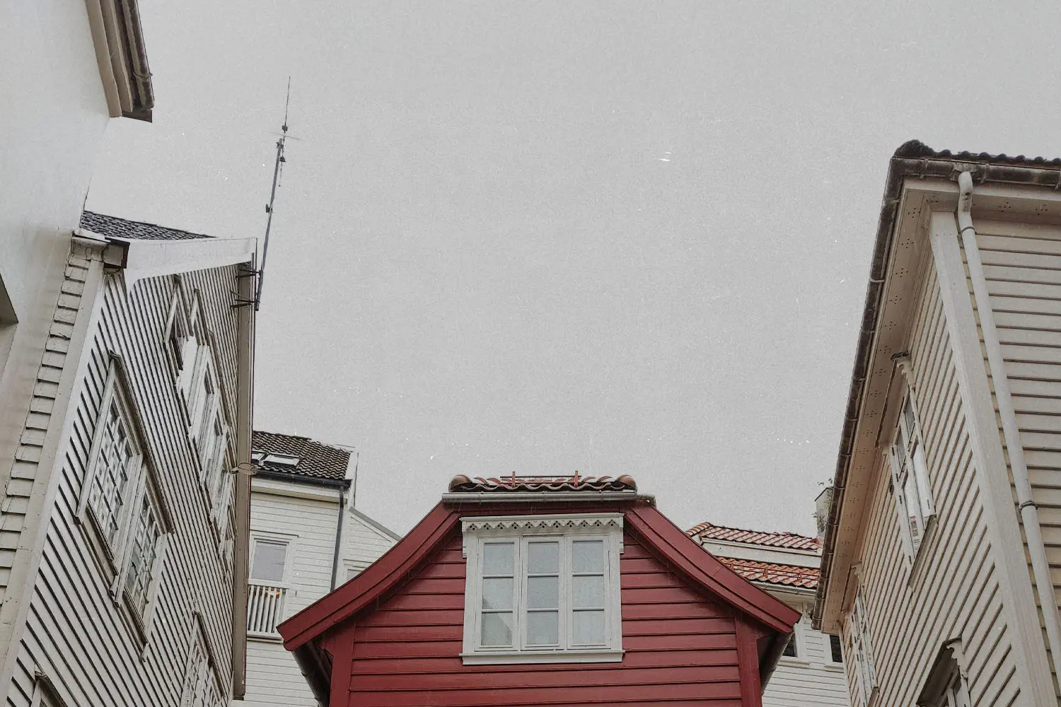 view of residential rooftops from the street with red home in the center