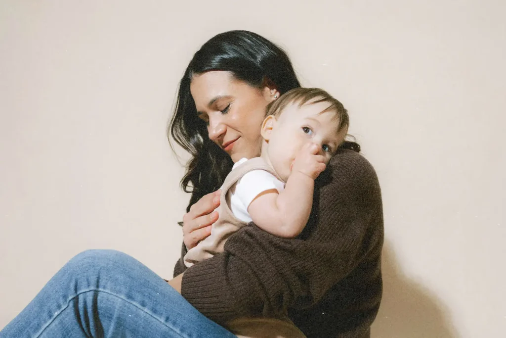 content young woman with dark hair holding a toddler