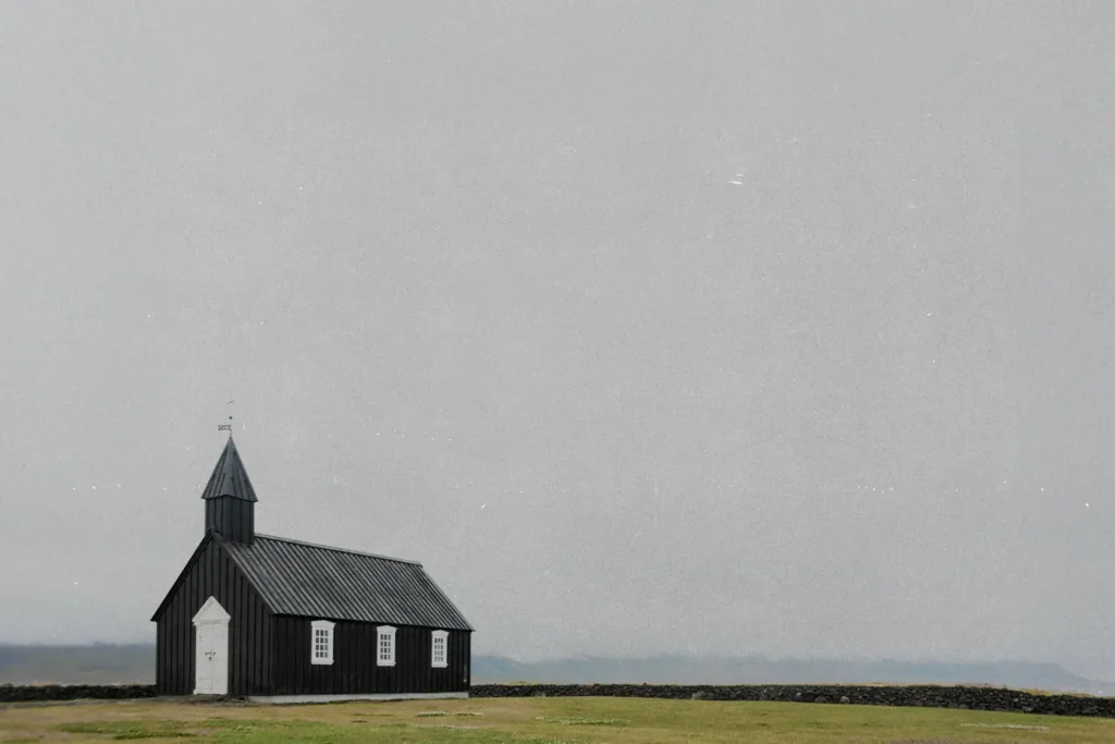 Rustic wooden church building in the distance of an open foggy field