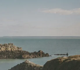boulders coming up from a calm ocean