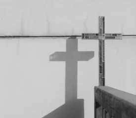 Wooden cross and its shadow displayed on a wall