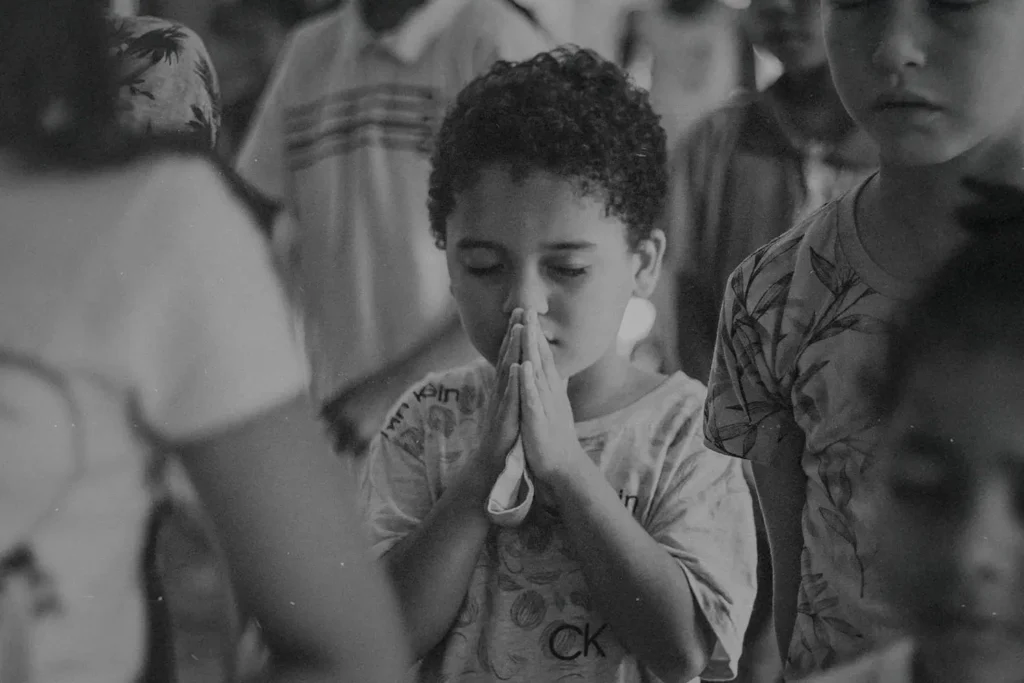 Little boy with eyes shut tightly and folded hands in prayer
