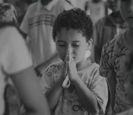 Little boy with eyes shut tightly and folded hands in prayer
