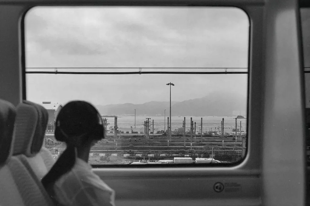 Girl with headphones on looking out a train window towards the city