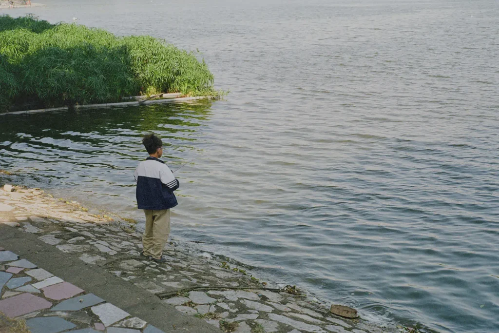 child fishing at the edge of water