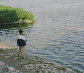 child fishing at the edge of water