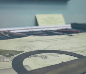 A drafting table with architectural drawings, rulers, and measuring tools arranged across the surface