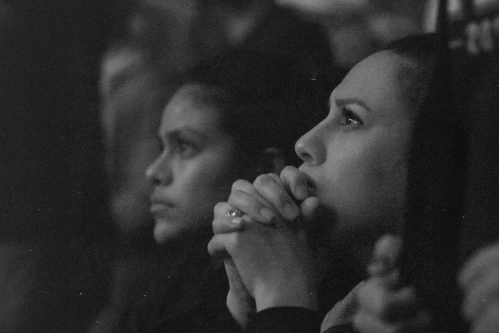 Two women looking focused towards the distance, one with hands folded on her chin
