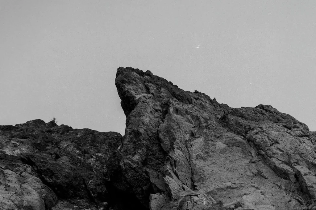 Jagged rock formation rising sharply against a clear sky in a black‑and‑white landscape