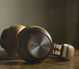 Close-up of brown over‑ear headphones resting on a wooden surface in soft, warm light