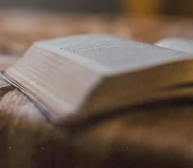 Bible lying open on a textured blanket with pages softly illuminated