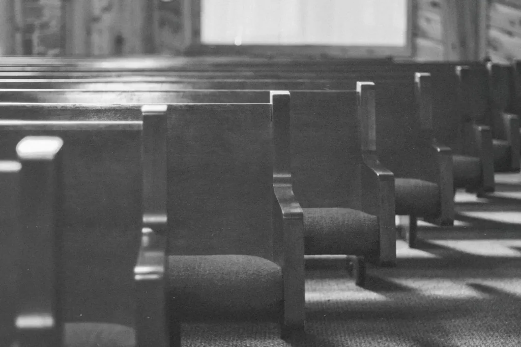black and white photo of empty church pews