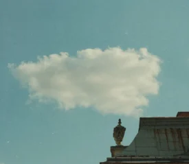 Single cloud in the sky behind building roof