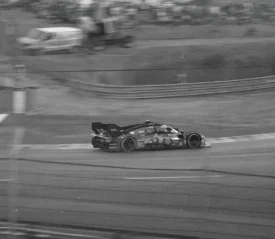 black and white photo of race car driving on track