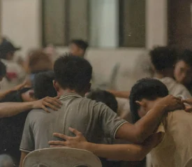 group of people with hands on each others shoulder with heads down