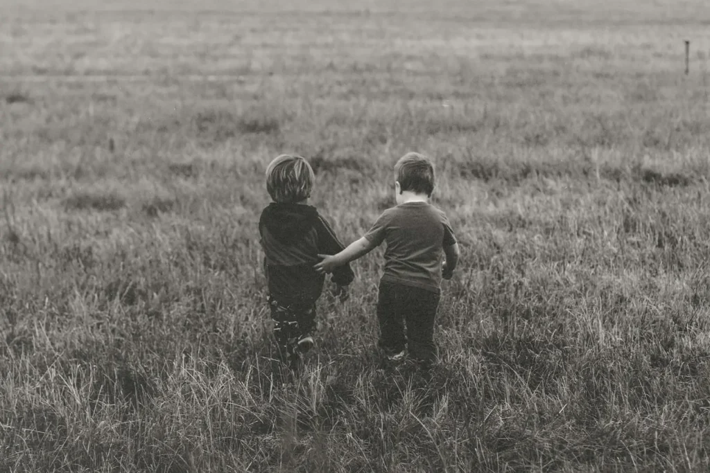 Two kids walking through a field