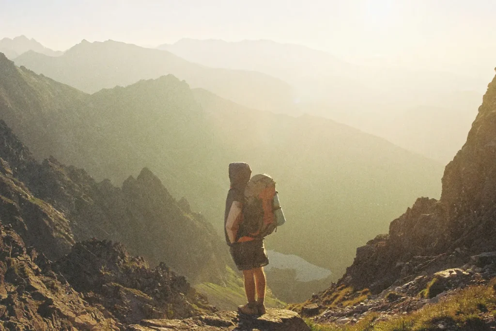 Man with camping gear looking out into the horizon with mountains in the background