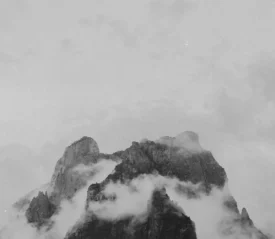 Black and white image of fog resting on mountain peak