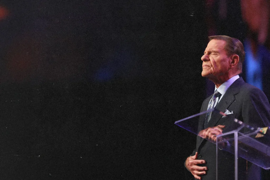Kenneth Copeland praying at pulpit with black background
