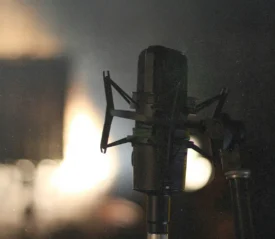 Studio microphone in soft focus with warm backlighting in a dim recording space