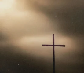 Sunlight shining through the clouds to highlight a wooden cross