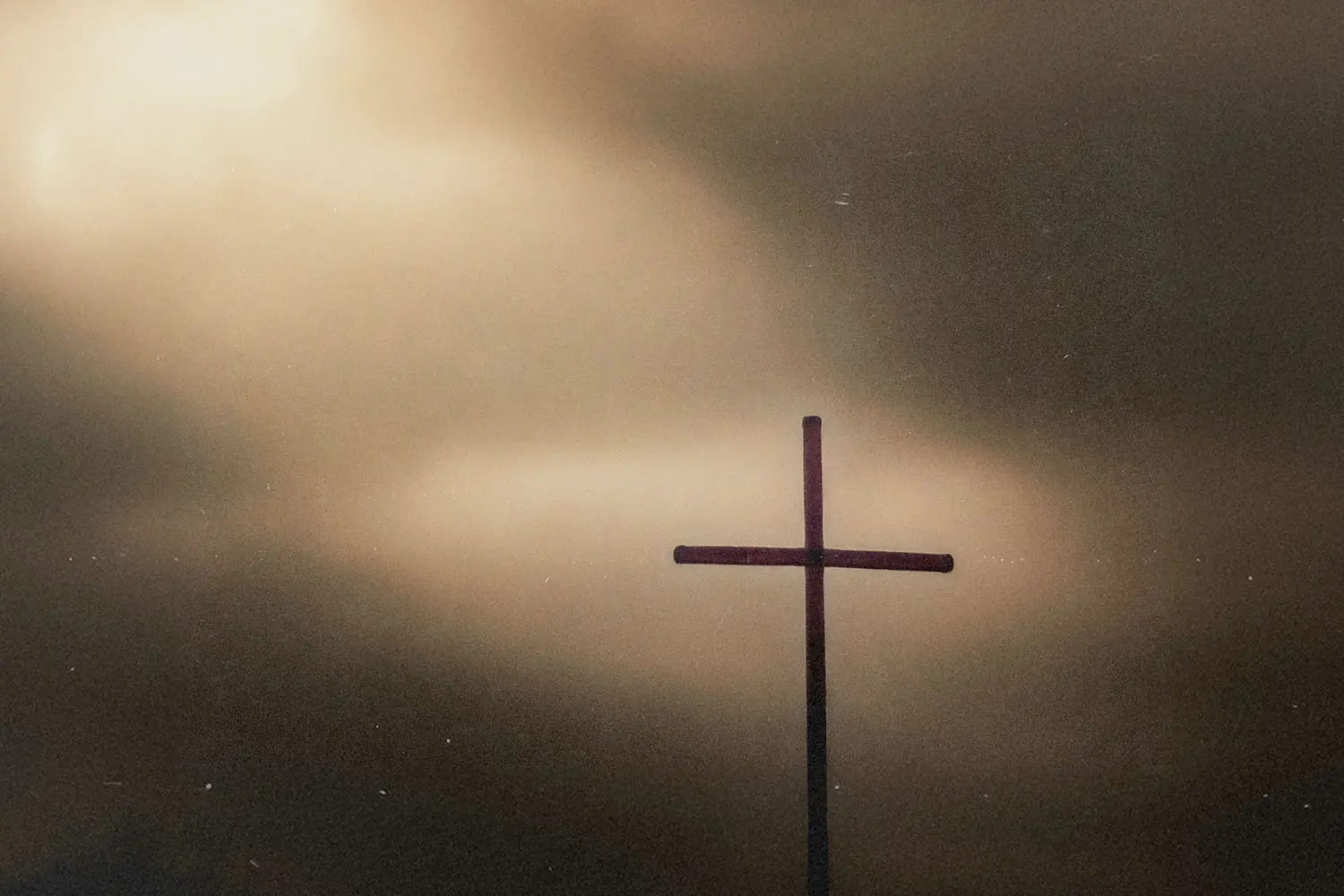 Sunlight shining through the clouds to highlight a wooden cross