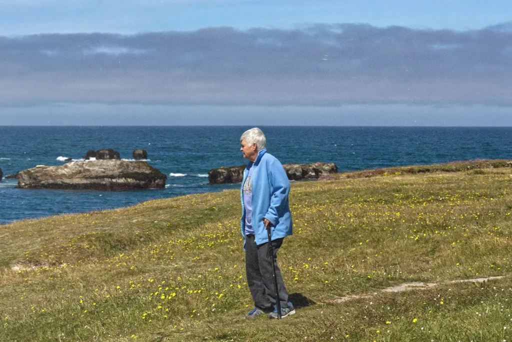 Man standing on grass looking out to a lake