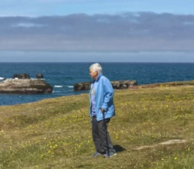 Man standing on grass looking out to a lake