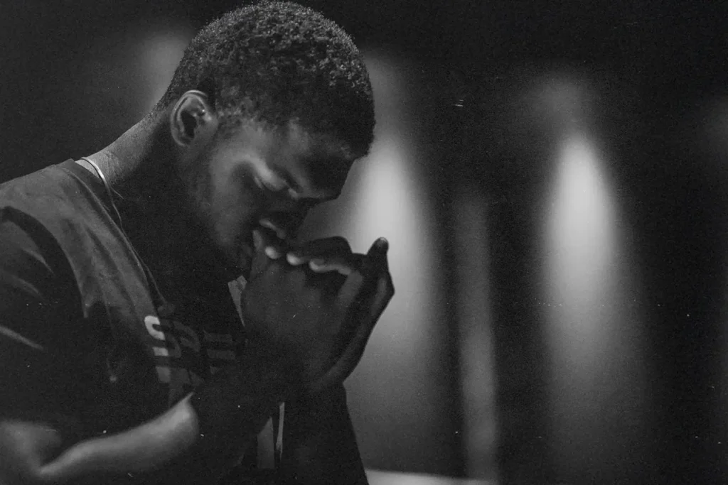 Man with head bowed and hands clasped to pray