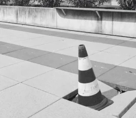 caution cone in a broken block of pavement