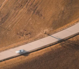 Blurred car driving on a open road with dry farm lands on both sides