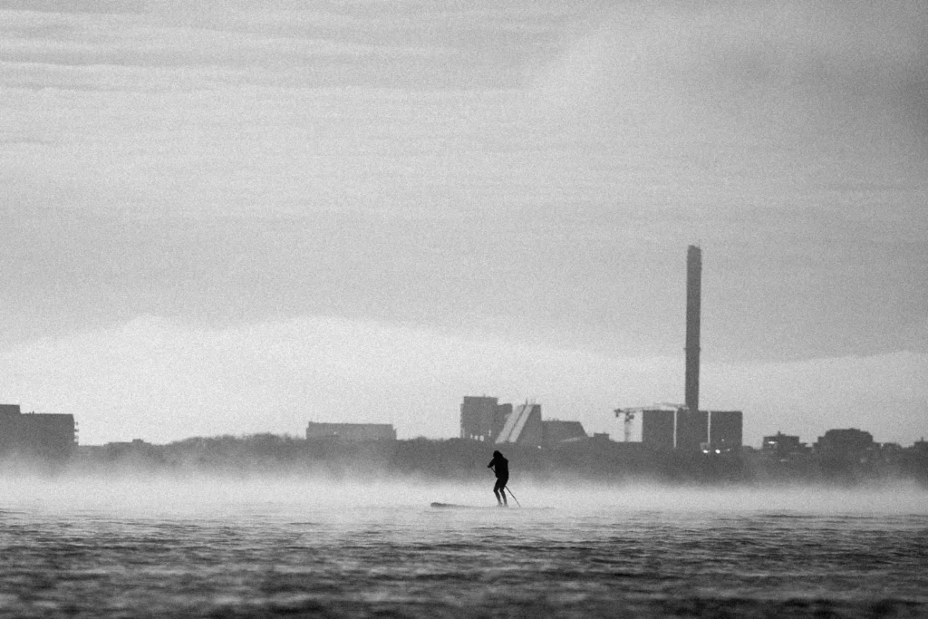 Person standup paddle boarding in the middle of rushing waters