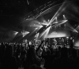 Crowd of people worshiping as band sings on stage