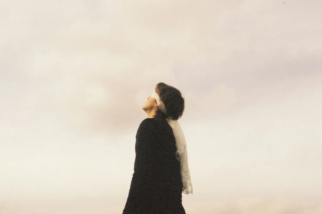 blindfolded person looking up at a white sky