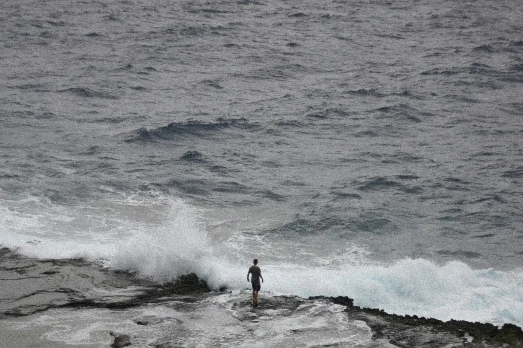 Person standing on the shore of crashing waves