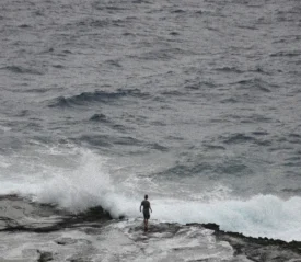 Person standing on the shore of crashing waves