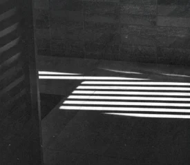 Bright horizontal light beams creating striped shadows across a tiled floor and wall