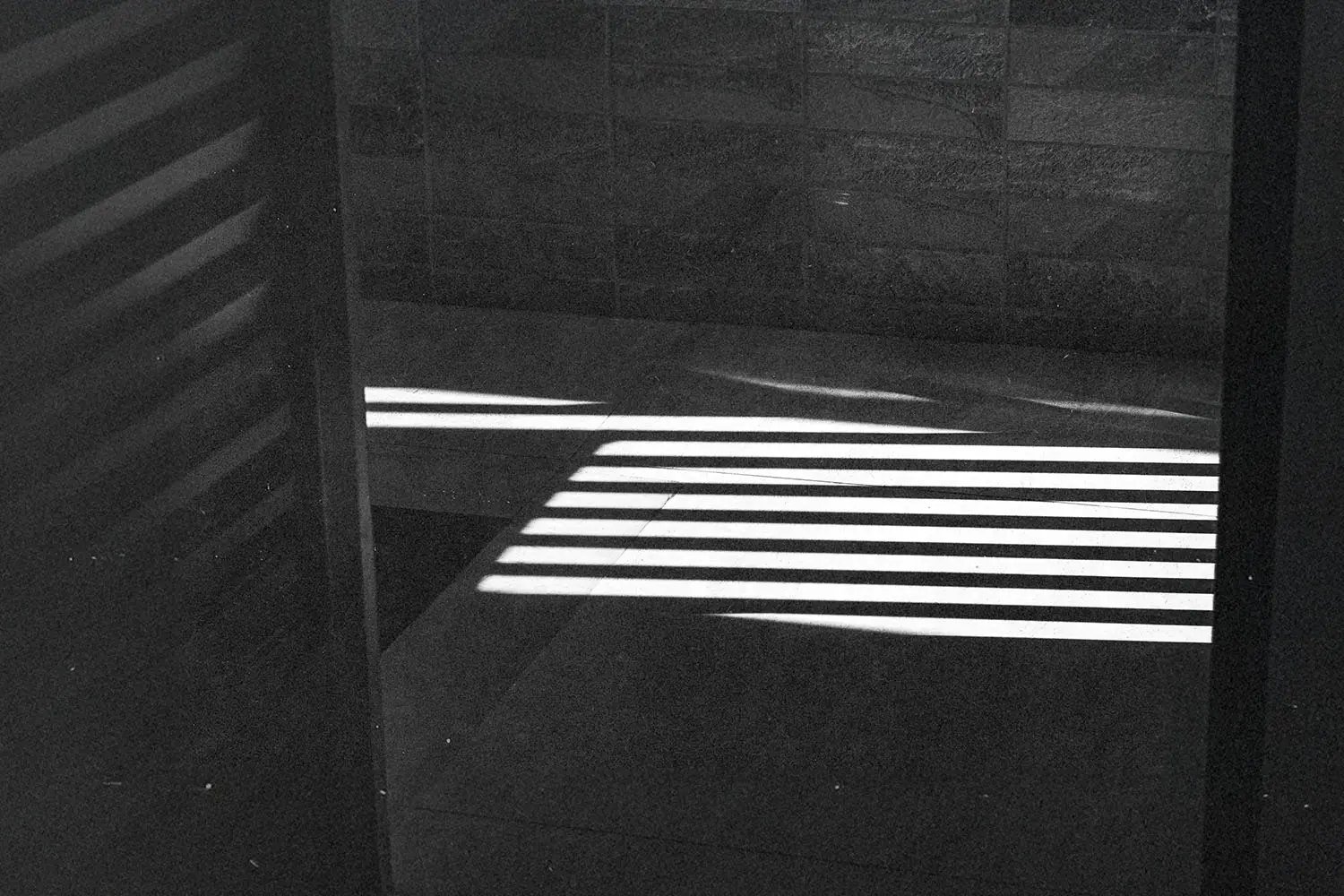 Bright horizontal light beams creating striped shadows across a tiled floor and wall