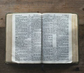 Open Bible displaying passages from Proverbs on a rustic wooden table