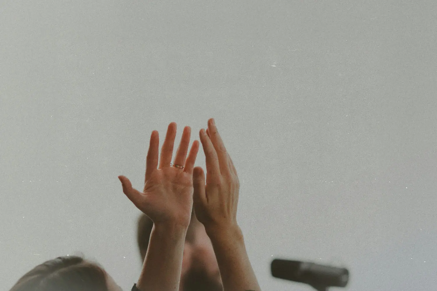 Two hands lifted upward in a gesture of worship or praise against a plain background