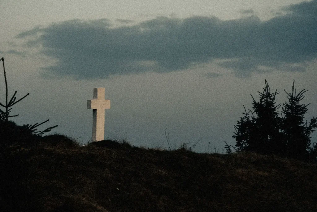 stone cross outside among short trees