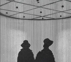 Silhouettes of two people standing beneath a striped, geometric installation with dramatic lighting
