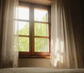 Sunlight shining through window with white curtains flowing in the wind